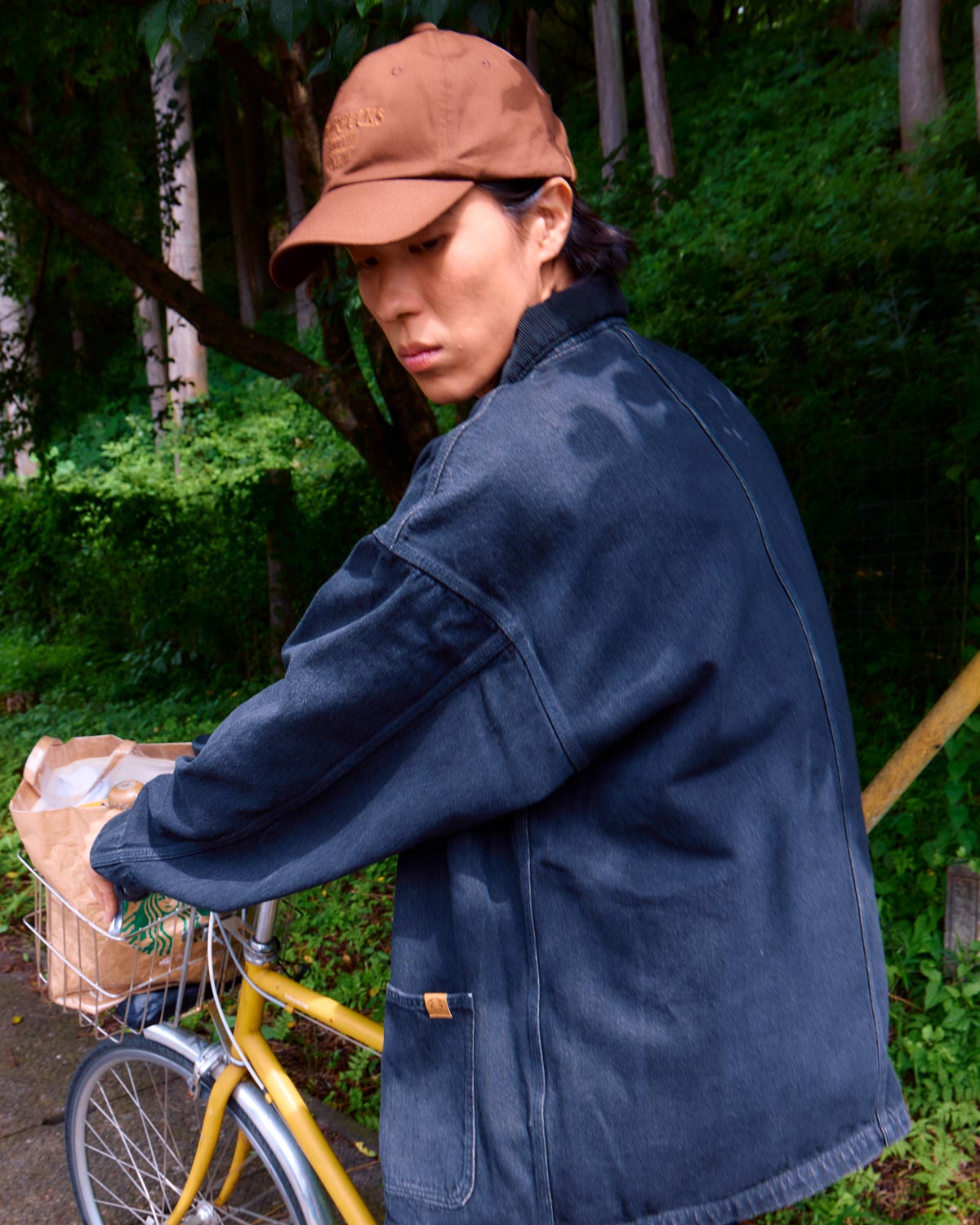 〈STARBUCKS STAND by BEAMS〉ブラックデニムカバーオールを着用した男性