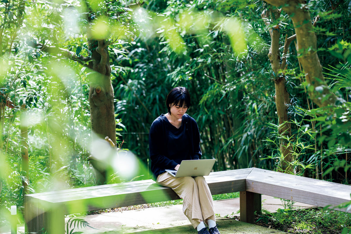 庭のベンチでPC作業中の女性