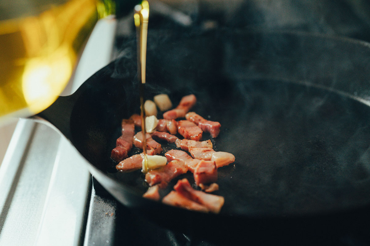 フライパンにパンチェッタとオリーブオイルを入れる様子