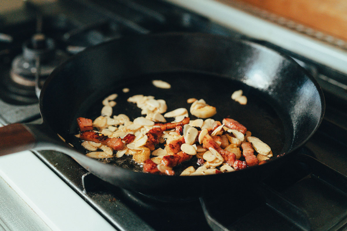 パンチェッタ、オリーブオイル、ニンニク、アーモンドを炒める様子