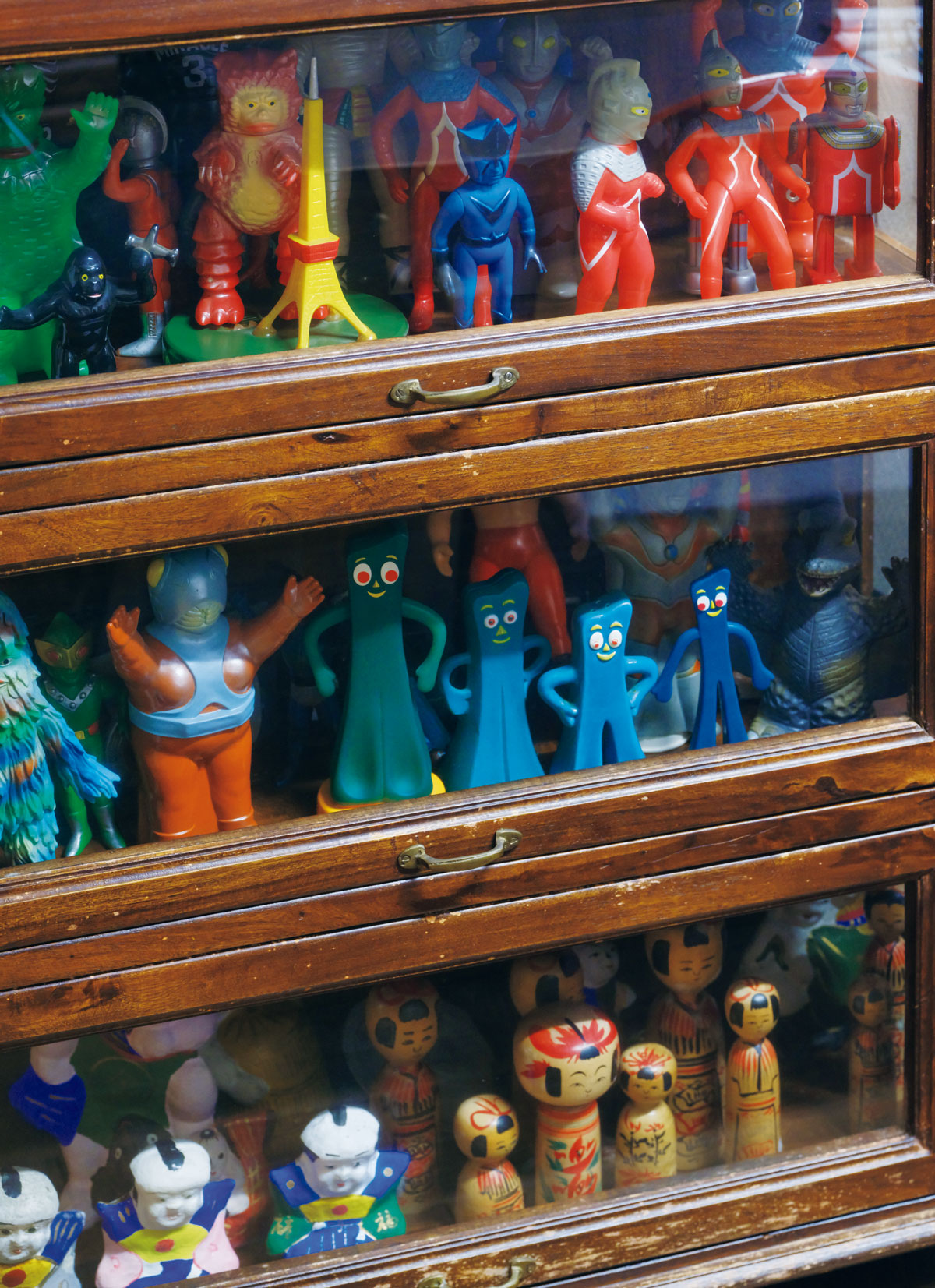 ウルトラマンや怪獣人形のソフビ、アメリカのク レイアニメキャラ、ガンビー人形などが置かれた棚